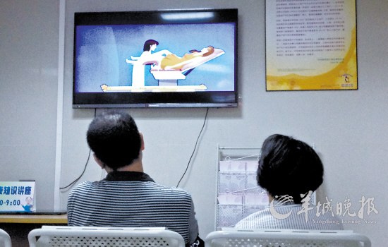 兩名家屬坐在佛山市婦幼保健院藥流室外一邊等待做手術的病人,一邊看著電視上的人工流產宣傳片